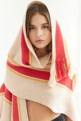Ruana artesanal color beige con rayas horizontales rojas y amarillas, y flecos en el borde inferior.