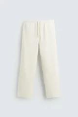 Pantalón jogger color crudo, de corte recto, con cintura elástica ajustable con cordón, bolsillos frontales y traseros.