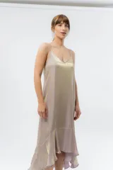 Vestido midi color lila metálico de breteles finos regulables, escote en V y ruedo asimétrico con leve vuelo.