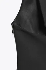 Top color rosa pálido, con cuello halter y escote en pico. Presenta un lazo en la espalda y cierre lateral con cremallera oculta.