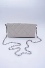 Cartera de cuero color marrón claro, con diseño capitoneado y cadena metálica plateada removible. Tiene ranuras interiores para tarjetas y documentos, y forro textil rojo.