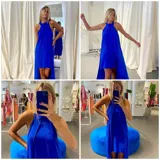 Vestido azul eléctrico con cuello halter, corte irregular y capa corta en la parte delantera y larga en la parte trasera.