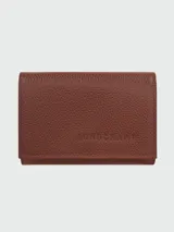 Billetera compacta de cuero granulado color marrón, con solapa frontal y logo Longchamp grabado en el centro.