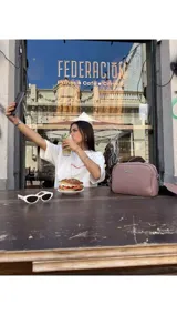 Bandolera pequeña de textura símil cuero color caramelo/marrón, con dos compartimentos principales con cierre. Correa ancha ajustable de tela negra con inscripción en relieve.