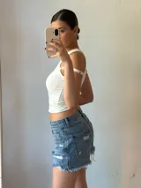 Musculosa blanca con cuello redondo y breteles anchos con ojales metálicos.