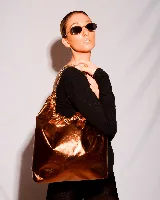 Bolso tipo tote de cuero color cobre, con fruncido superior y cadena dorada como asa.