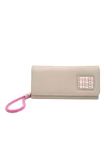 Billetera de cuero sintético color beige con cierre de solapa y broche a presión. Tiene un dije colgante de cordón rosado y un aplique con el logo de la marca en el frente.