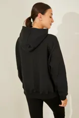 Buzo negro de frisa oversize con capucha y bordado de moño print animal en gamuza en el delantero.