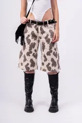 Bermuda de jean color beige con estampado de manchas marrones tipo vaca, tiro alto, corte ancho y largo a la rodilla.