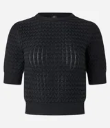 Blusa negra de manga corta con cuello redondo y textura de punto con patrón de corazones o escamas.