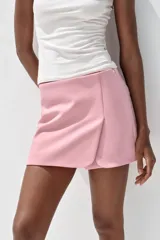 Falda pantalón corta color rosado, de tiro medio con abertura en el delantero y cierre lateral con cremallera.