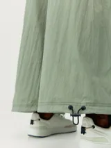 Pantalón estilo paracaídas color verde claro, de tejido técnico Wind_S, con bolsillos laterales y reguladores en la cinturilla y en el bajo.