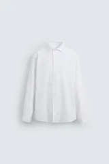 Camisa blanca de corte regular, cuello italiano, manga larga con puños abotonados y cierre frontal con botones.