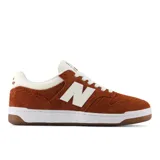 Championes New Balance modelo 480, color marrón óxido con detalles en blanco crema. Presentan un diseño de corte bajo con capellada de gamuza y logo 'N' en el lateral. La suela es blanca con una banda de goma marrón en la parte inferior.