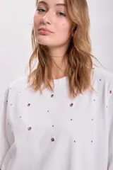 Remera blanca de corte holgado con mangas cortas y detalle de ojalillos metálicos en el frente.