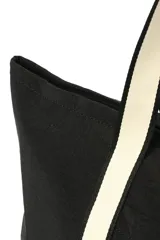 Bolso negro tipo tote con asas de hombro de cinta blanca. Tiene un bolsillo externo con botón a presión y cierre superior con cremallera.