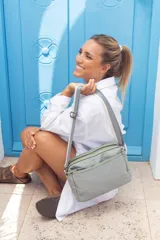 Bandolera color beige con correa de galón a tono, dos bolsillos frontales con cierre y uno dorsal. Su bolsillo principal incluye reparticiones internas.