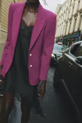 Blazer negra entallada con cuello solapa, manga larga con hombreras, bolsillos delanteros con solapa y cierre frontal con botones dorados.