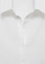 Camisa blanca de lino, de corte oversize, manga larga con puños abotonados, cuello camisero y cierre frontal con botones.