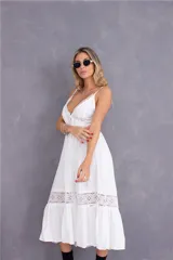 Vestido largo blanco con breteles finos, escote en V con detalle de puntilla, corte imperio con bordado en la cintura y falda con volados y detalle de puntilla en el ruedo.
