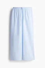 Pantalón de pijama de corte holgado en algodón a rayas celestes y blancas. Modelo de tiro bajo con elástico revestido en la cintura, cordón para ajustar fino y piernas rectas, levemente acampanadas.