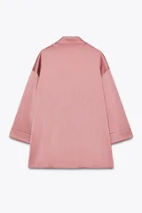 Blazer rosado de cuello solapa y manga tres cuartos con vuelta. Tejido con efecto arrugado y cierre cruzado con botones negros.