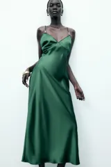 Vestido midi verde esmeralda de satén, con escote en pico, tirantes finos regulables con apliques dorados y cierre lateral con cremallera oculta.