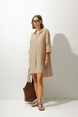 Vestido tipo camisa color beige, de lino, con cuello camisero, mangas 3/4 y cierre frontal con botones.