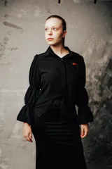 Camisa negra de algodón con cuello clásico, mangas largas abullonadas con puños elásticos y cierre frontal con botones.