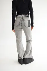 Pantalón de jean gris de corte acampanado, con tiro alto y costuras verticales al frente.