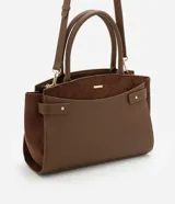 Cartera satchel mediana color marrón, confeccionada en cuero sintético con detalles en gamuza. Cuenta con asas medianas, cierre de cremallera y detalles metálicos dorados. Incluye correa extraíble y regulable.