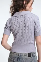 Top tejido de punto color lila con cuello polo y mangas cortas.