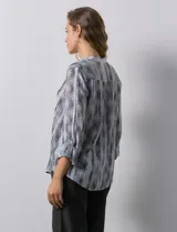 Blusa de gasa estampada con cuello a la base, escote en V y abertura central con botones. Delantera con plisados y mangas 3/4 regulables con presilla y botón.