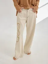 Pantalón de lino color beige con bordado artesanal de líneas onduladas en color marrón.