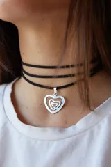 Gargantilla de tiento sintético negro con dije de laberinto con forma de corazón en acero quirúrgico plateado.