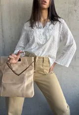Blusa blanca de algodón con bordado broderie, escote en V y mangas largas.