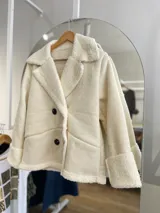 Chaqueta marrón con forro tipo corderito, doble botonadura y cuello con solapas.