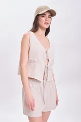 Top sin mangas color crudo con rayas verticales finas en color beige, escote en V con lazos ajustables y corte crop.