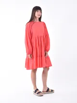 Vestido corto color coral, con cuello redondo, mangas abullonadas 3/4 y falda escalonada de tres niveles.