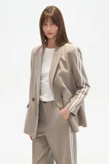 Blazer cruzado de color beige claro, con cuello solapa, dos botones frontales y bolsillos con tapa.