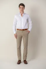 Pantalón de vestir color beige, de corte clásico, con bolsillos laterales y traseros. Se ajusta a la cintura con cinturón de cuero marrón.