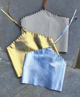 Top corto de cuero sintético dorado con escote halter y tiras finas para atar en la nuca y la espalda.