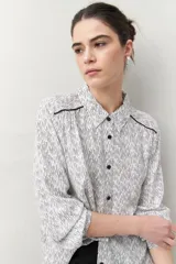 Camisa de manga larga con estampado paisley en tonos azul y blanco, cuello camisero y cierre frontal con botones.