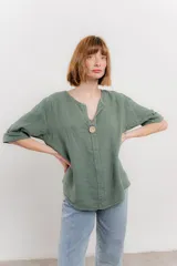 Blusa celeste de lino, con escote en V, manga tres cuartos y botón de madera.
