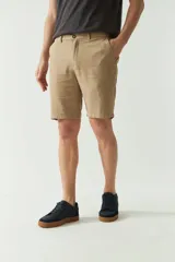 Bermuda de lino y algodón color beige, con bolsillos laterales y traseros, cierre con botón y presillas para cinturón.