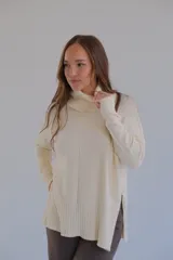 Sweater color crema de corte recto con cuello alto y aberturas laterales.