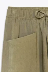Pantalón color verde oliva de tiro alto, corte ancho y largo 7/8. Tiene cintura elástica ajustable con cordón, bolsillos de plastrón en delantero y espalda.