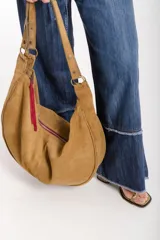 Cartera hobo grande de cuero descarne color marrón, con correa de hombro ajustable y cierre superior con cremallera.