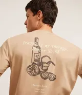 Remera color beige de algodón, corte clásico, cuello redondo y manga corta. Estampa pequeña en el pecho con diseño de botella y lettering.
