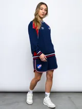 Short deportivo azul marino con ribetes blancos y rojos, y escudo del Club Nacional de Football bordado en la pierna derecha.